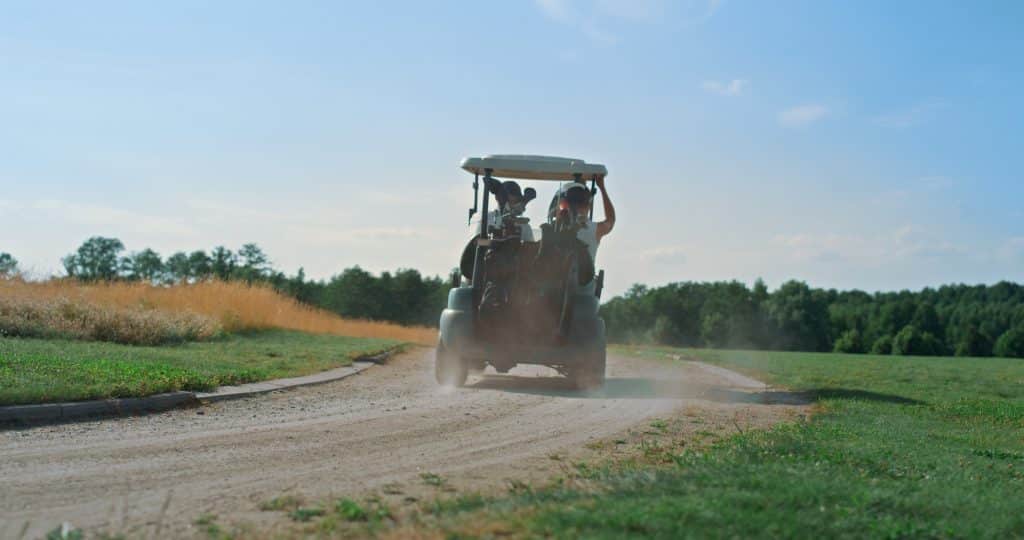 Golf couple driving cart on fairway Players team ride buggy car on summer day